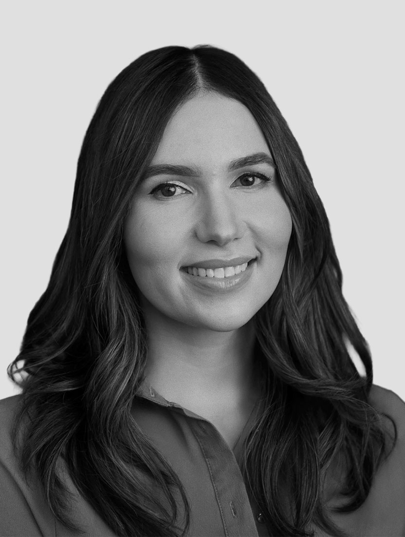 Black and white headshot of a woman with long, wavy dark hair and a collared shirt.