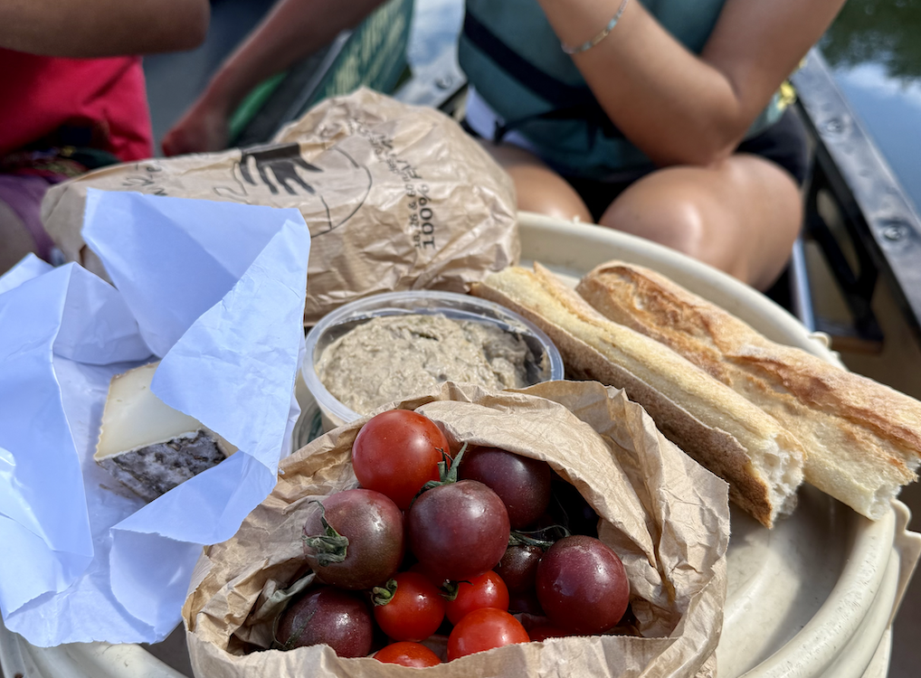 Un pique-nique de tomates, pain, fromage et sauce, posé dans un canoë.