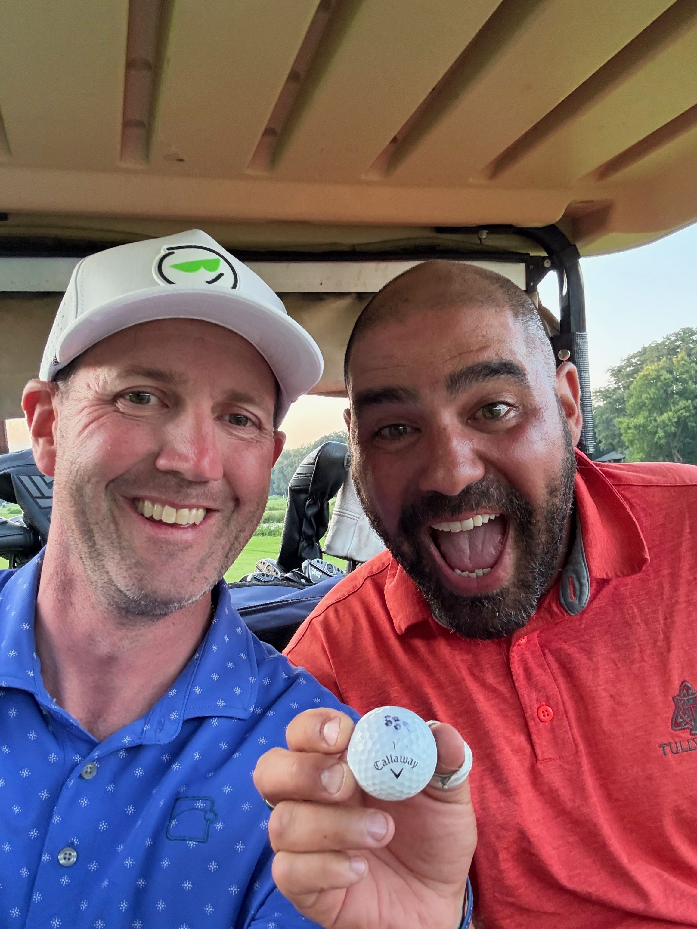 Sean Gouda holding a golf ball in a golf cart